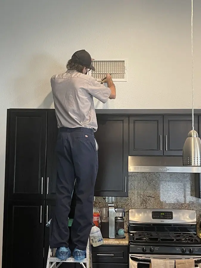 Technician inspecting an air vent during HVAC service in Weldon Spring